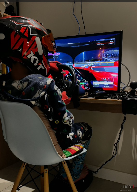 Henrique treinando no simulador em casa, de pijama e capacete